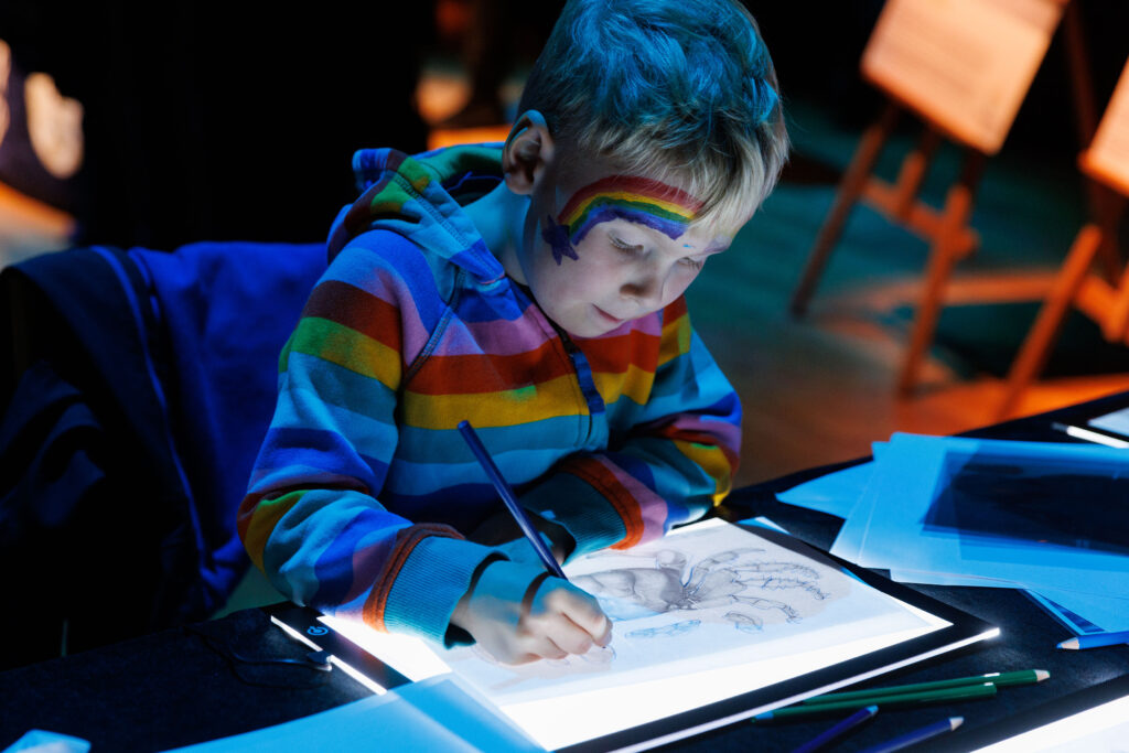 Boy using light box to draw crab